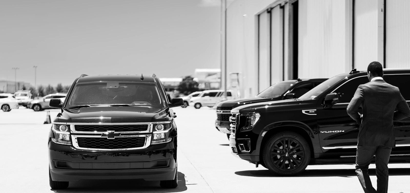 Professional walking past a row of black SUVs at an event motorcade